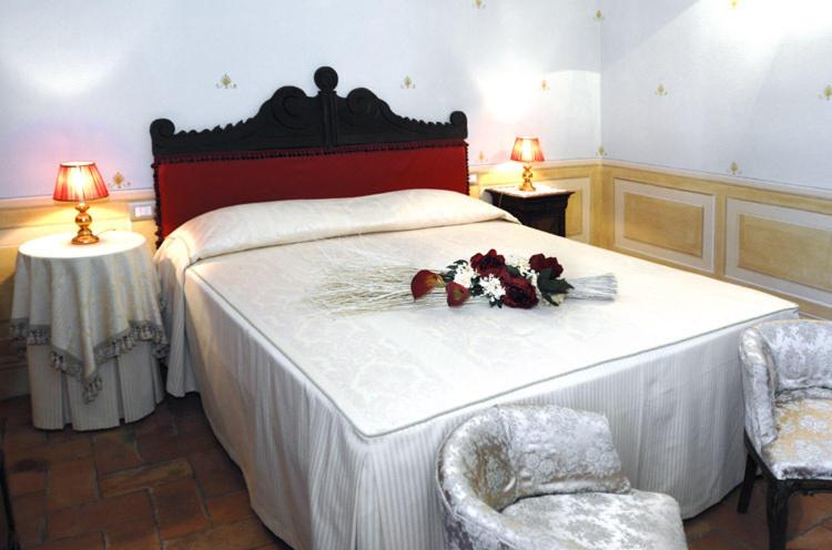 圣奎里科-多尔恰安蒂卡绍斯塔住宿加早餐旅馆的一间卧室配有鲜花床和两把椅子