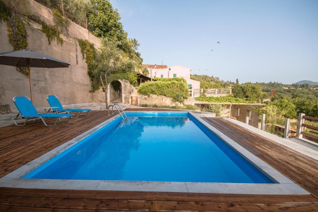 BastoúnionCorfu Tramezzo designer's House的蓝色的大型游泳池,配有蓝色的椅子和遮阳伞