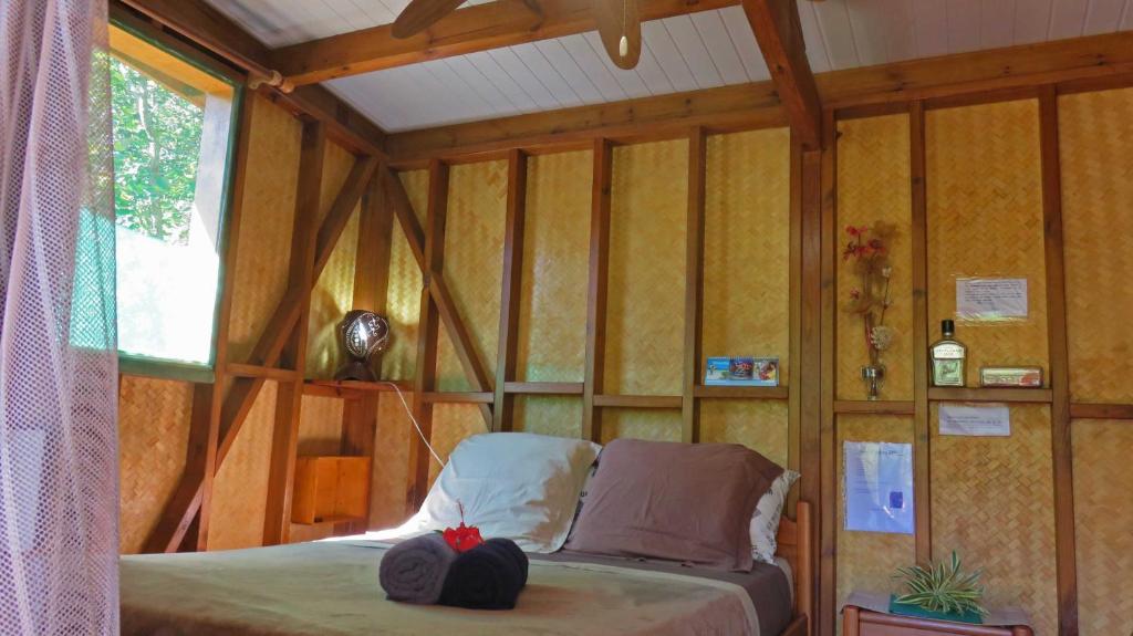 Dumbéala Cabane de la Vallee的卧室配有一张床铺,位于带木墙的房间内