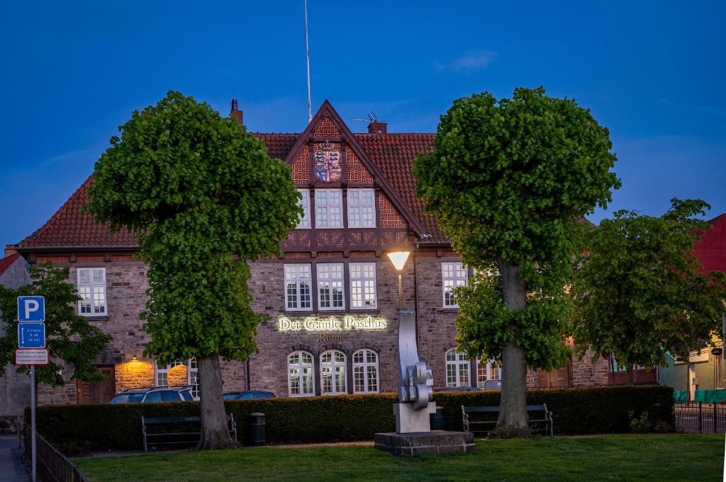 伦讷Det Gamle Posthus的一座大型砖砌建筑,前面有两棵树