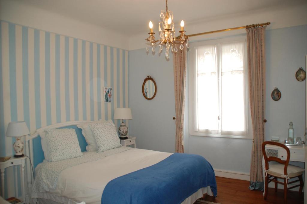 达克斯La Croix Blanche的一间卧室设有一张床、一个窗户和一个吊灯。