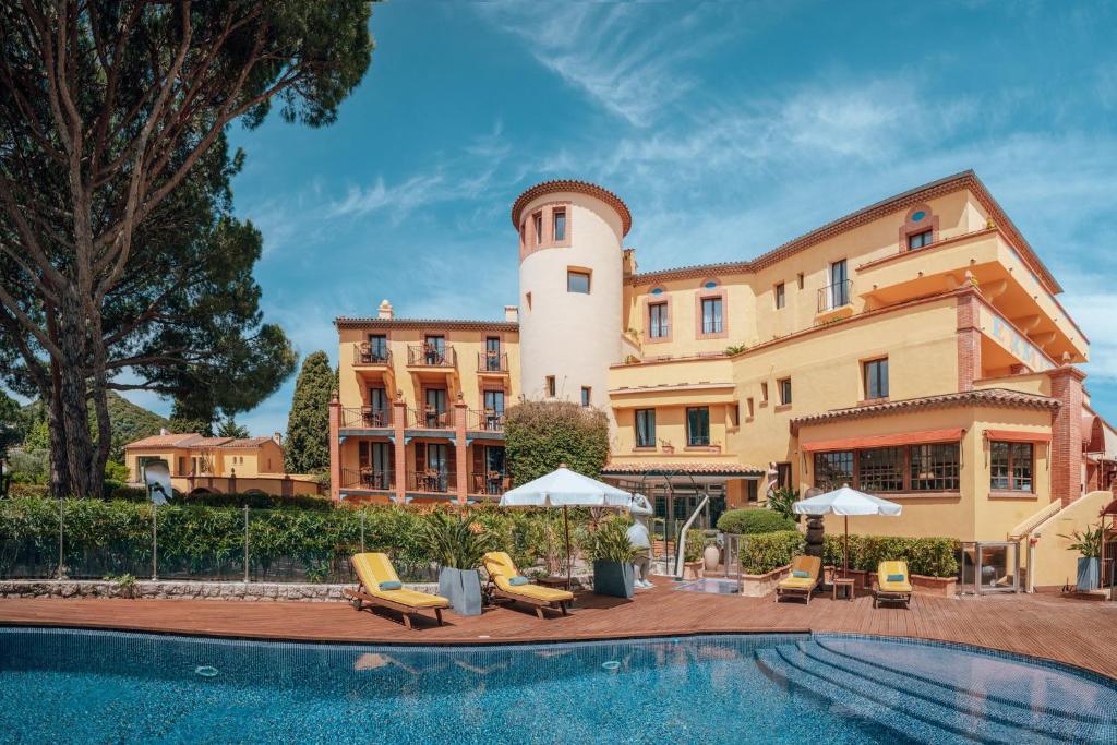曼德琉-拉纳普勒Ermitage de l'Oasis & Spa - Cannes Mandelieu的大楼前设有游泳池的酒店