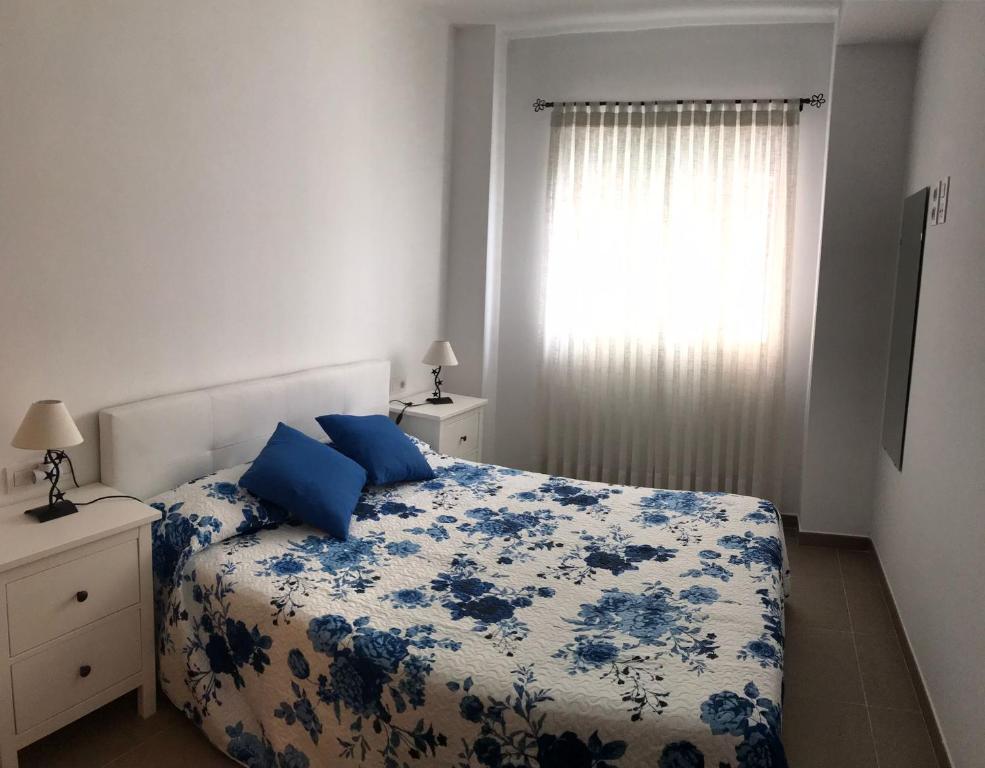 皮莱斯Apartamento en Piles Playa的卧室配有蓝色和白色的床和窗户。