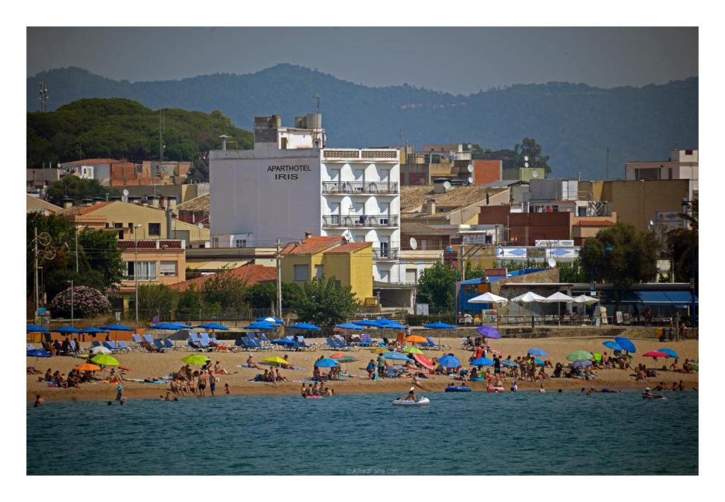 马尔格莱特德玛伊利斯公寓式酒店的一群人在海滩上,带遮阳伞