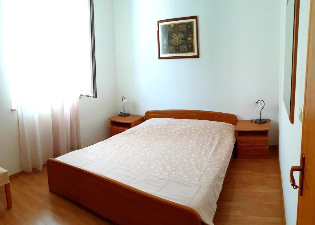 波尔Apartman Ivo, Bol的一间卧室设有床、两张桌子和一扇窗户