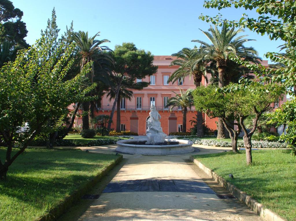 埃尔科拉诺密丽欧多罗公园酒店的棕榈树建筑前的喷泉