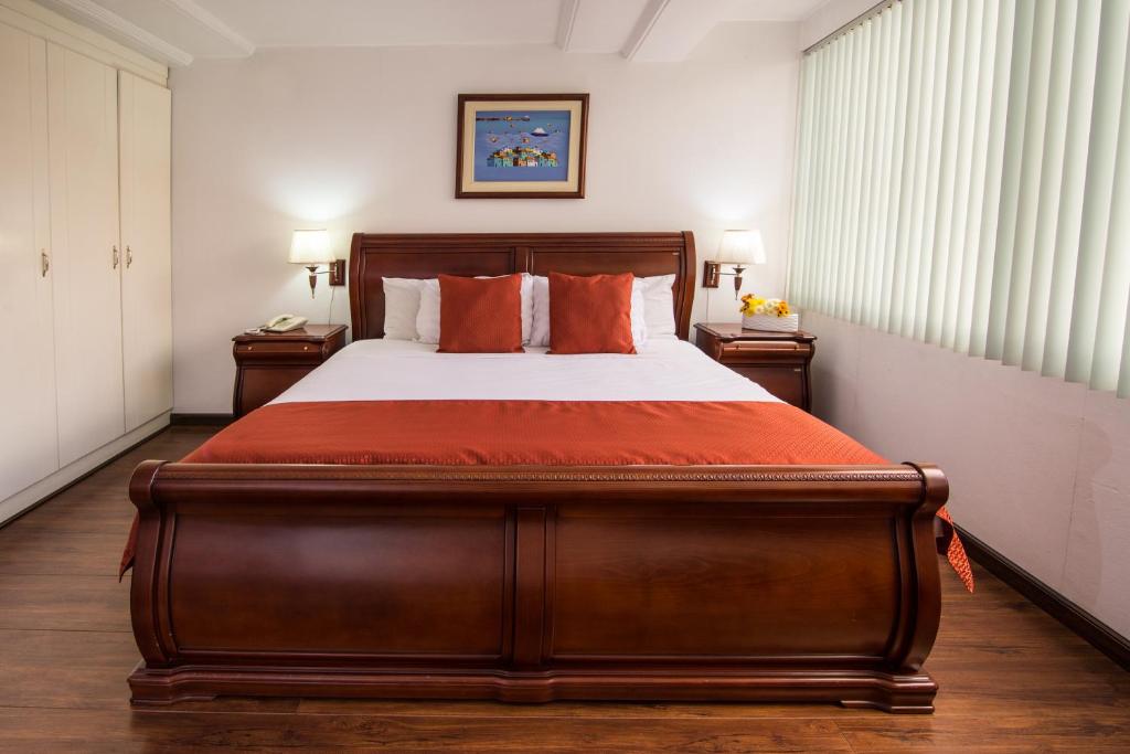 昆卡科尔德罗酒店 的一间卧室配有一张带橙色枕头的大型木制床。