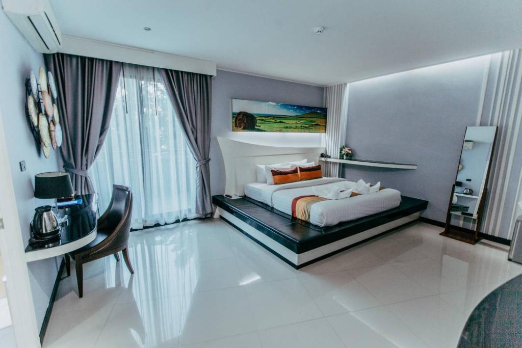 坤敬曼特拉瓦雷酒店的卧室配有1张床、1张桌子和1把椅子