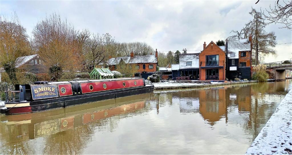 沃里克Smoke (Rowington Narrowboats)的船停靠在房子旁边的河流中