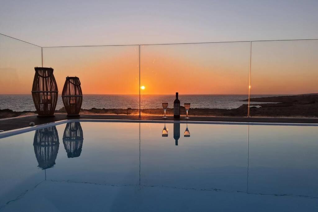 卡尔帕索斯Tramonto Luxury Villa No1- Breathtaking sunset view的站在游泳池旁,欣赏日落的人