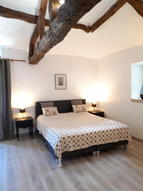 ValeillesDomaine de Merugat Chambre d'Hôtes的一间卧室配有一张床、两张桌子和两盏灯。