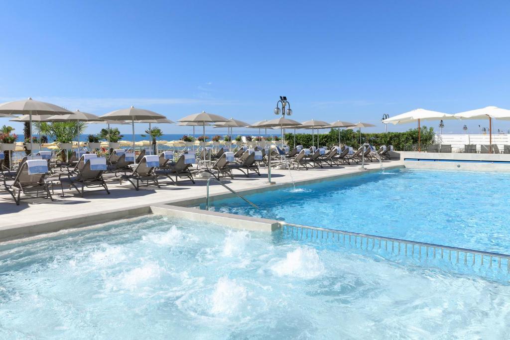 利多迪耶索罗卡瓦列利皇宫酒店的一个带椅子和遮阳伞的大型游泳池