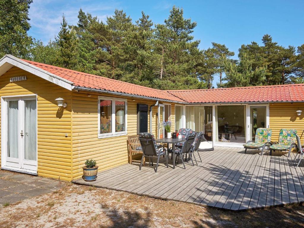 维斯特索马肯6 person holiday home in Aakirkeby的黄色的房子,设有一张桌子和椅子