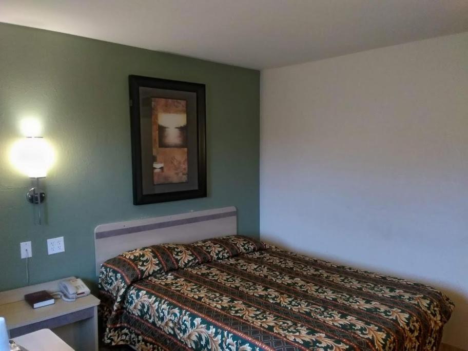 杰斐逊维尔RED CARPET INN LOUISVILLE NORTH -Jeffersonville In的酒店客房设有一张床,墙上挂着一张照片