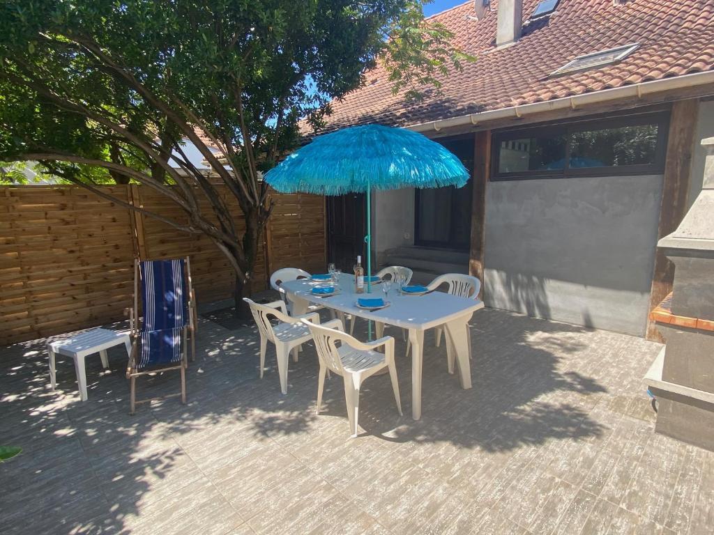 米米藏La Garluche的庭院内一张桌子和椅子,上面摆放着蓝色的遮阳伞