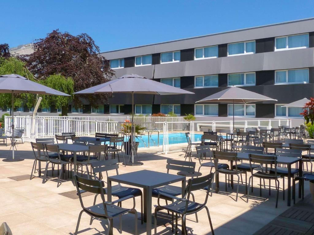 凯恩诺沃特冈科特纳克尔酒店的一组桌子和椅子,在建筑旁边,配有遮阳伞