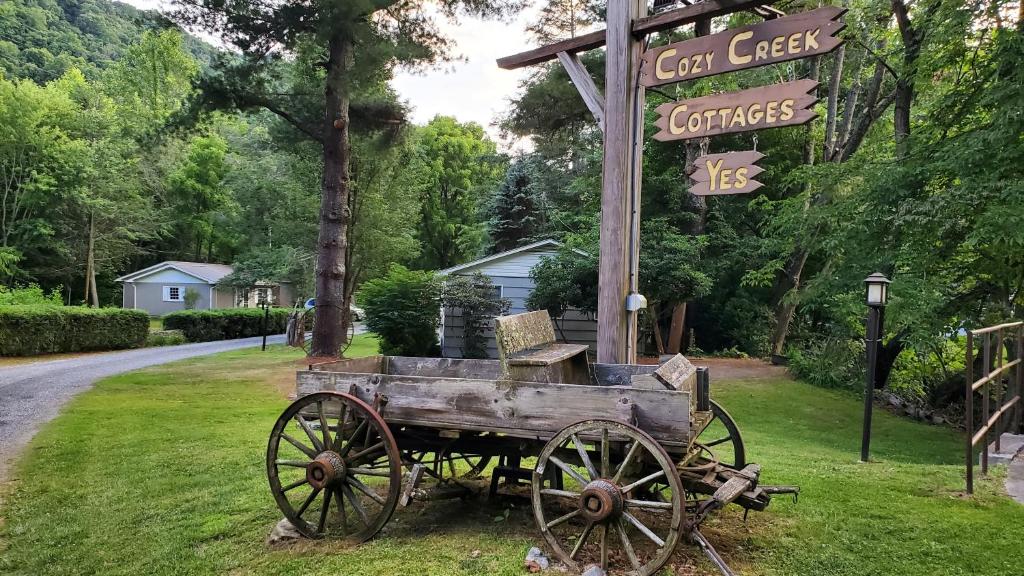 马吉谷Cozy Creek Cottages的坐在草上标志旁的木车