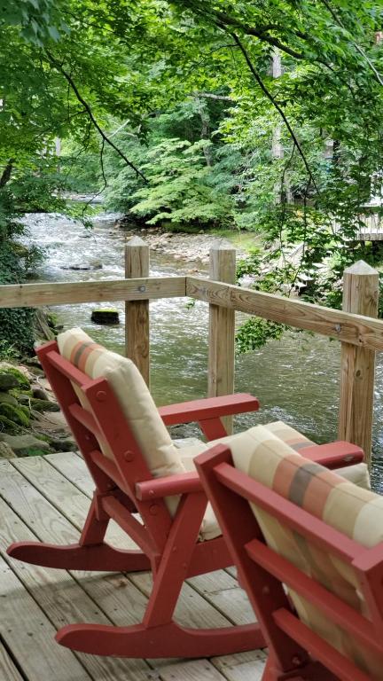 马吉谷Cozy Creek Cottages的两把椅子坐在水边的甲板上