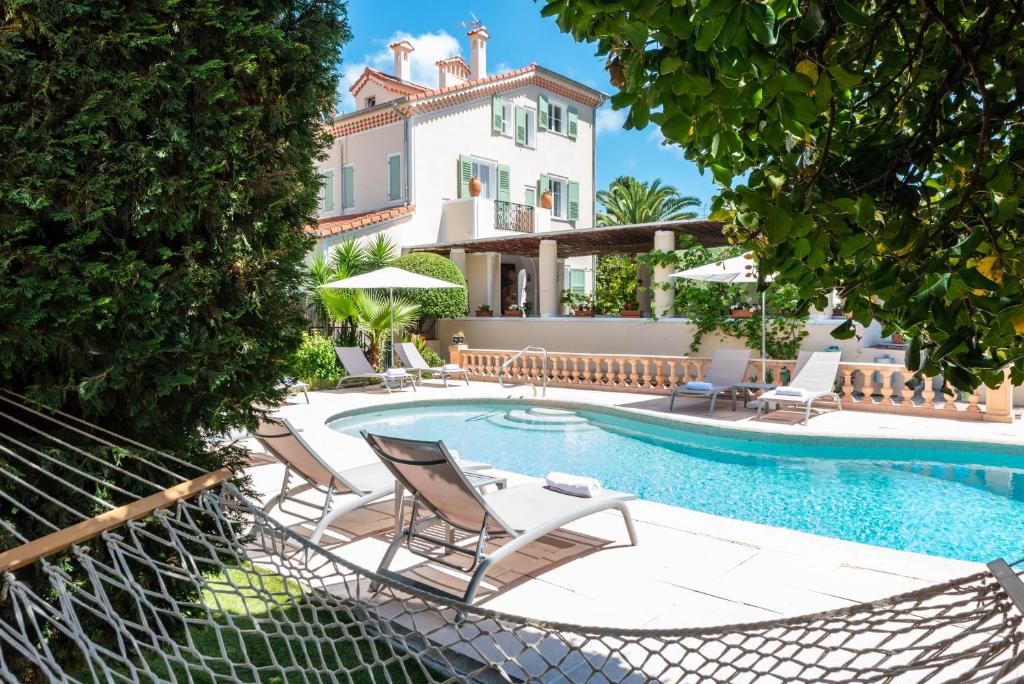 昂蒂布玛多利巴酒店的一个带椅子的游泳池以及一座房子