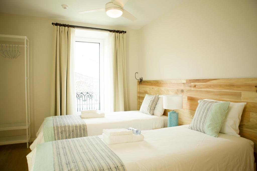 蓬塔德尔加达THE HOLY COW - Hostel & Suites的带窗户的客房内的两张床