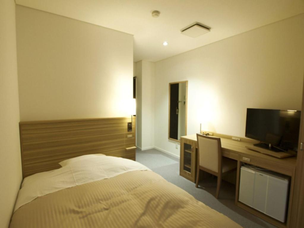 YabuPure Hotel - Vacation STAY 44183v的一间卧室配有一张床和一张书桌及电视