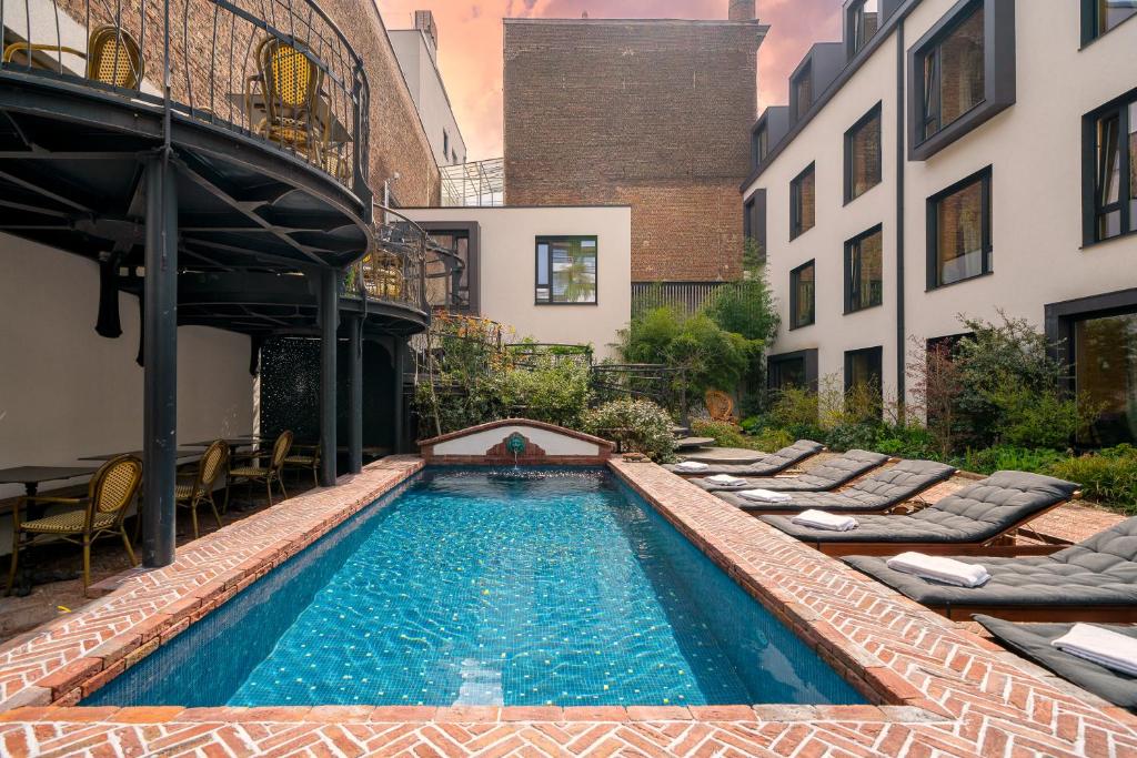 布鲁塞尔秘密花园酒店的一座带躺椅的游泳池,位于大楼旁