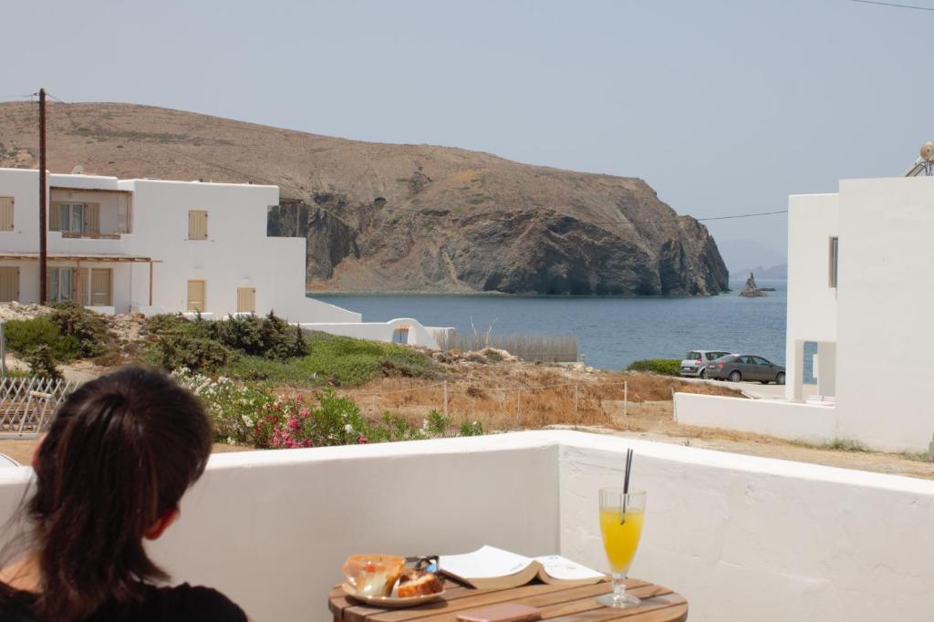 阿波罗尼亚V-rooms in Milos Cyclades的坐在桌子上看着大海的女人