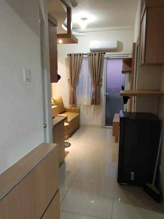 雅加达Apartemen Green Pramuka City的厨房以及带沙发和电视的客厅。