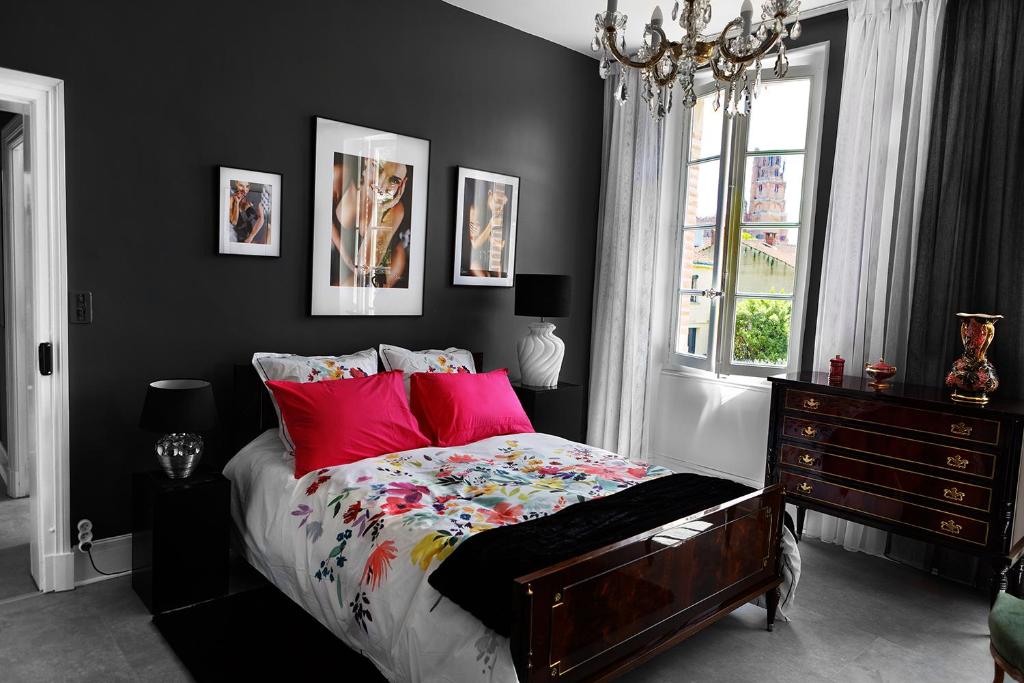 阿尔比LE CHERCHE MIDI Chambres d'hôtes avec CUISINE EQUIPEE grand jardin PARKING SECURISE GRATUIT的一间卧室配有一张带红色枕头的床和一扇窗户