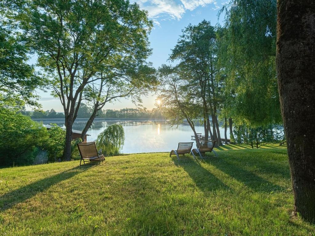 JabelScheune am Loppiner See的两个公园长椅坐在湖边的草地上