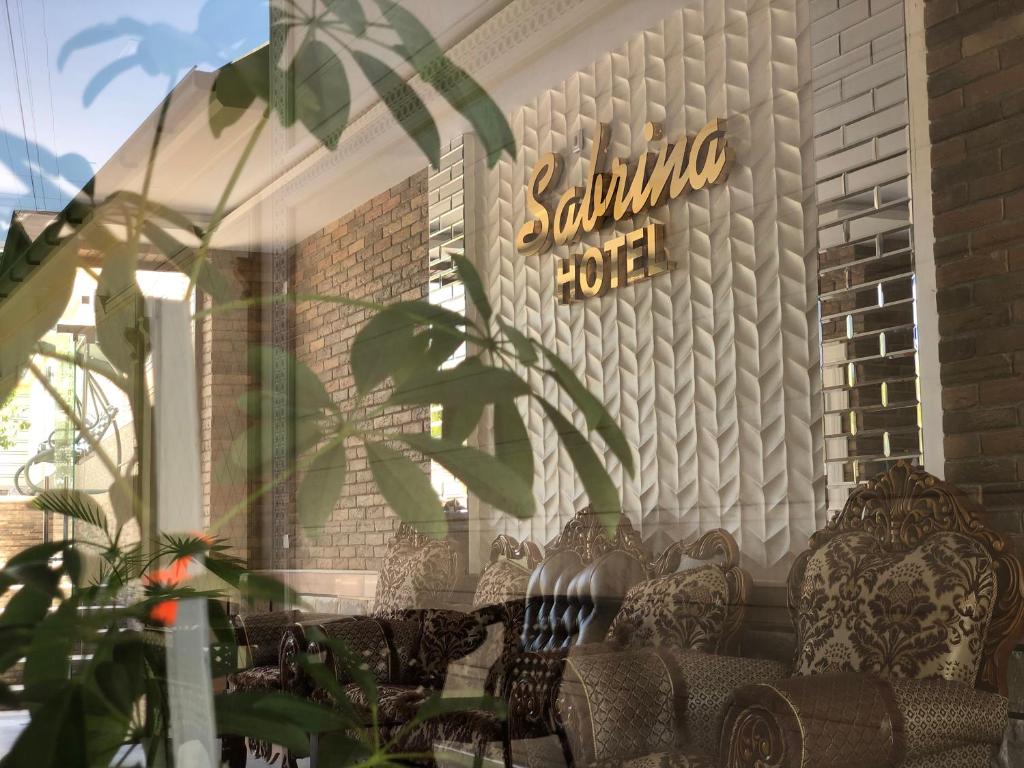 撒马尔罕Sabrina Hotel的商店前有椅子和墙上的标志