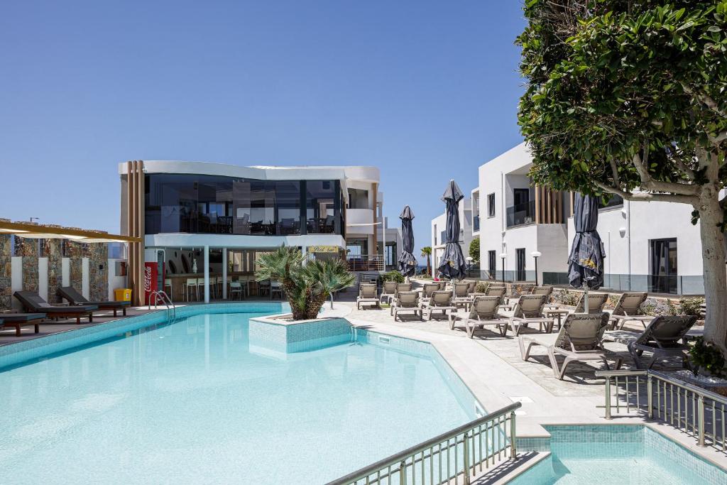 库基尼坎尼奥Golden Bay Boutique Hotel & Bungalows的一座带椅子的大型游泳池和一座建筑