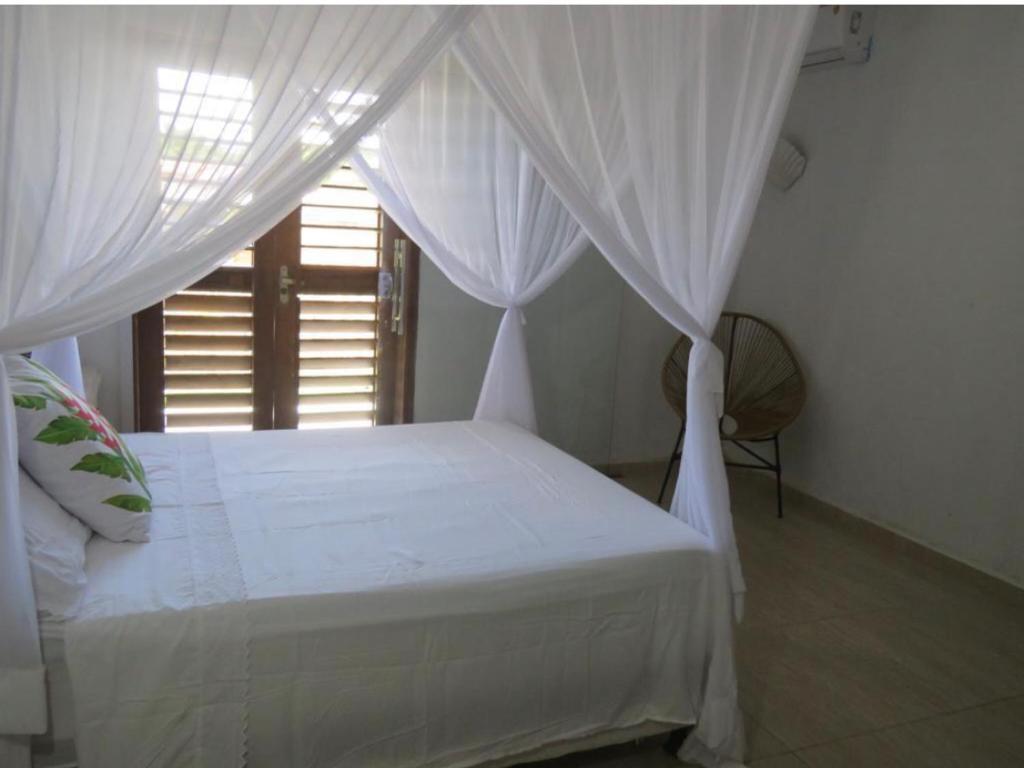 卡拉伊瓦Concept House Caraiva的卧室配有带白色窗帘的床和窗户。