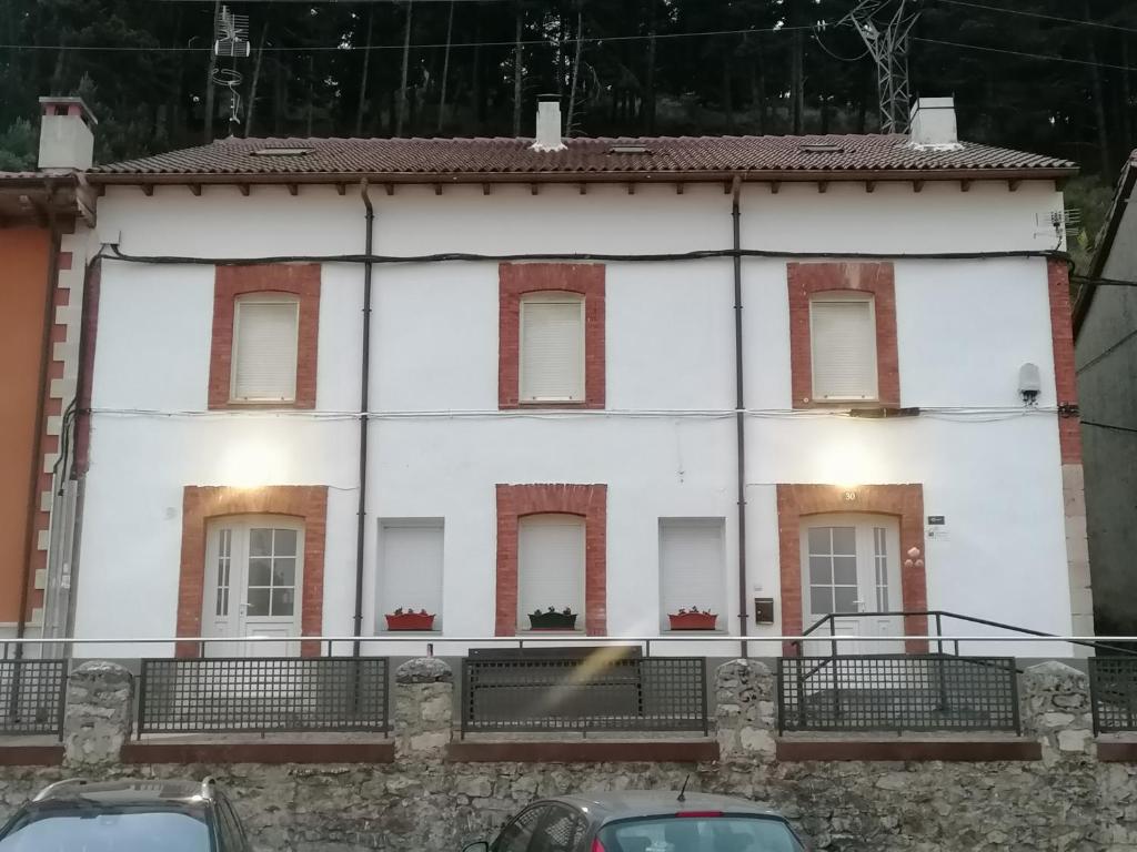 皮苏埃加河畔塞尔韦拉Albergue Cervera de Pisuerga的白色的房子,有窗户,汽车停在前面