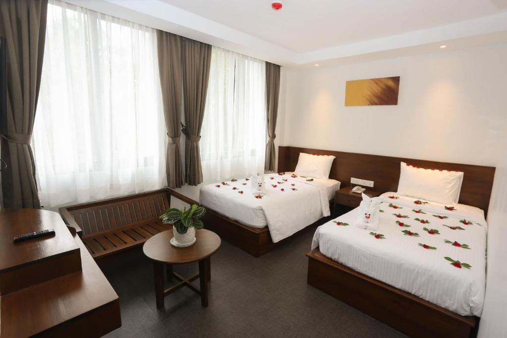 仰光Yangon Win Hotel的酒店客房设有两张床和一张桌子。