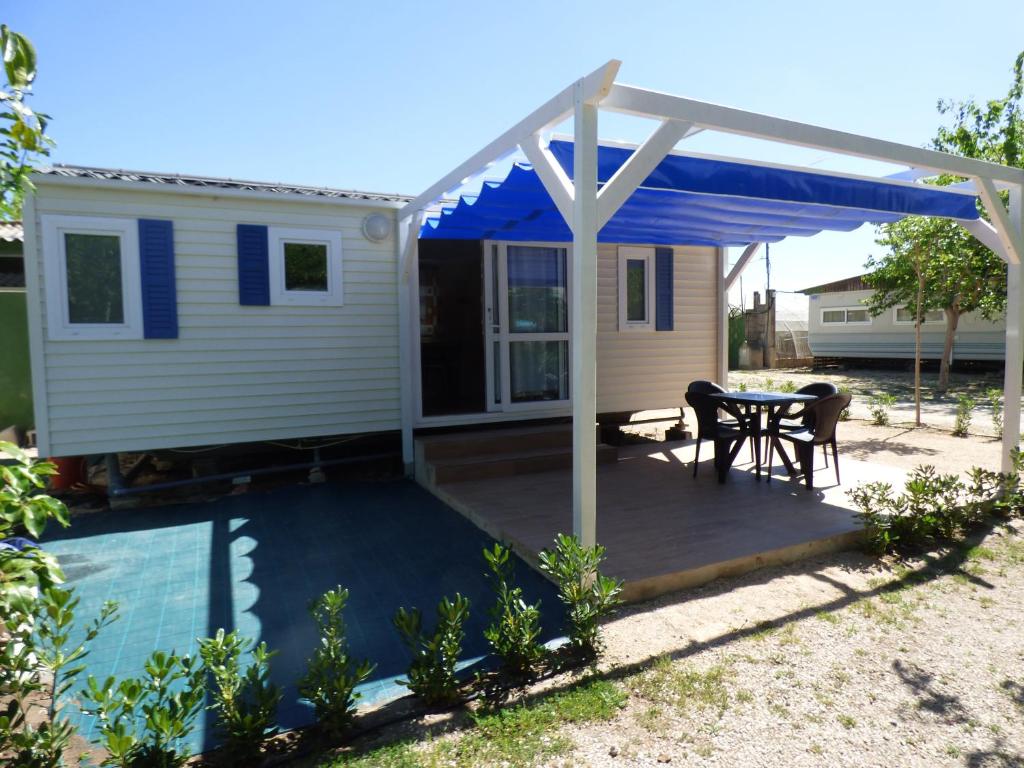 苏埃卡Camping Barraquetes的天井配有桌子和蓝色遮阳篷