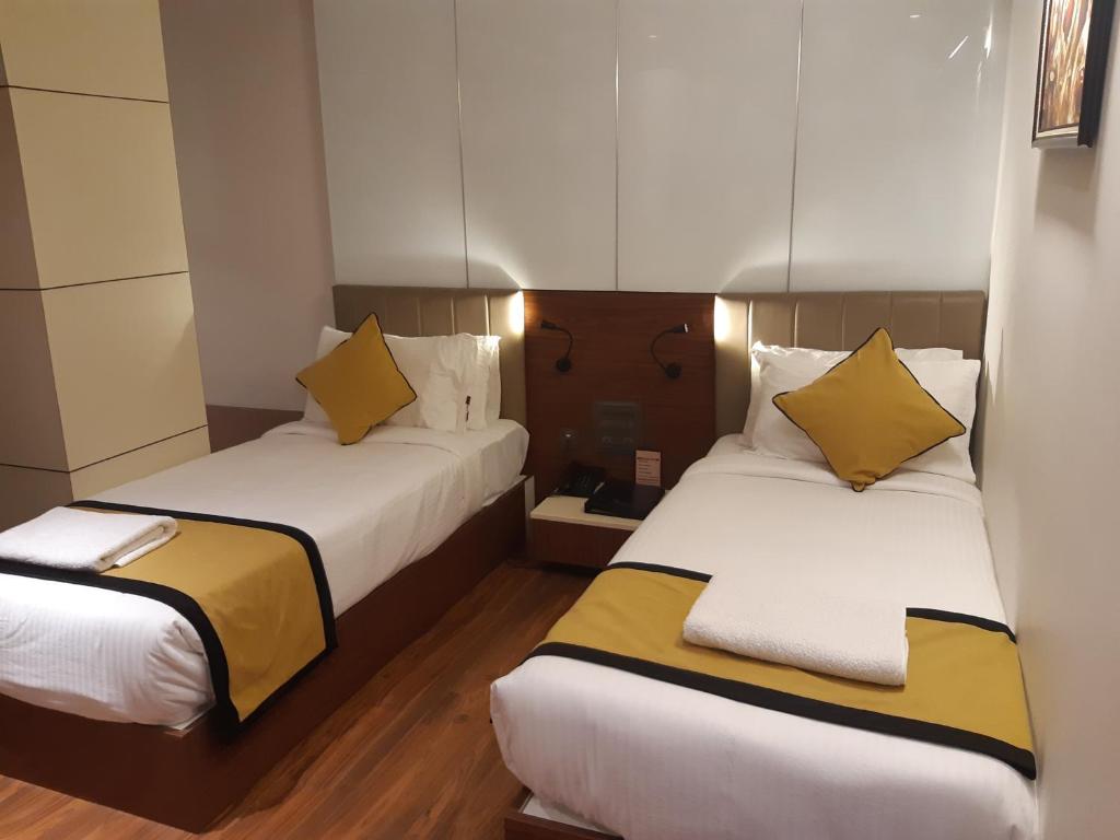 维杰亚瓦达Hotel Namo Residency的配有黄色枕头的酒店客房的两张床