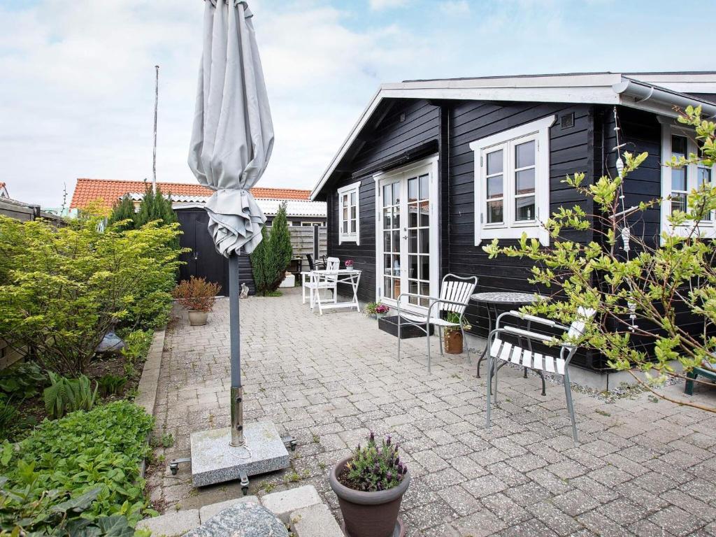 KarrebæksmindeHoliday home Karrebæksminde XLIV的黑色房子前带雨伞的庭院