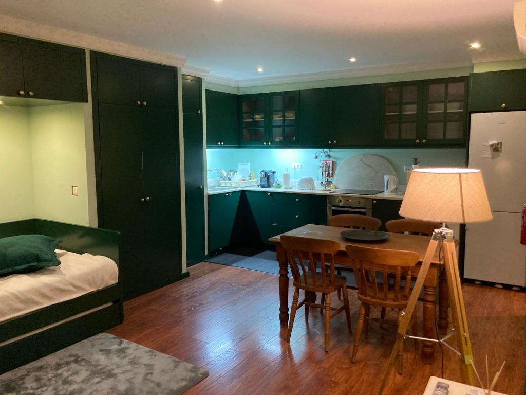 丰沙尔Studio by Casa da Quinta的厨房配有绿色橱柜、桌子和床。