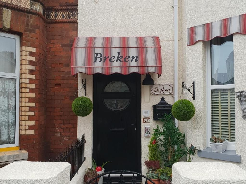 埃克斯茅斯Breken Guest House的一间面包店的黑色门,有红色和白色遮阳篷