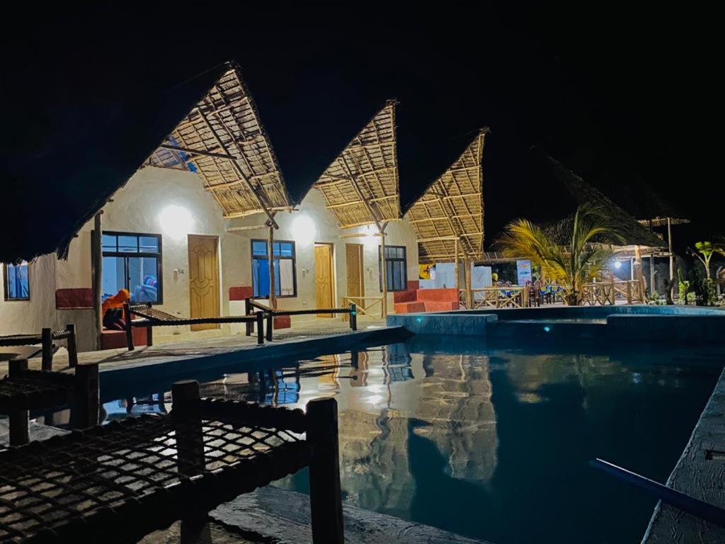 江比阿Mkeka Spice Lodge Jambiani的一座游泳池,在晚上在建筑物前