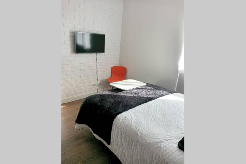 科恰班巴Estudio Monoambiente的一间卧室配有一张床和一张红色椅子