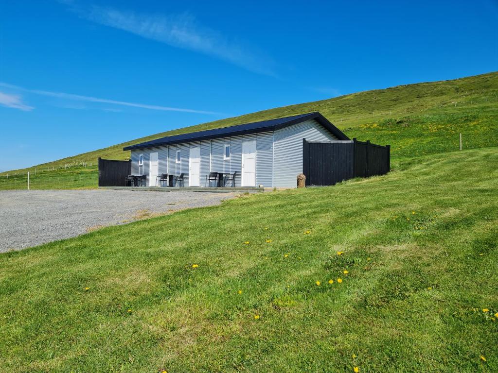 AðaldalurGuesthouse Brúnahlíð的草山顶上的白色建筑