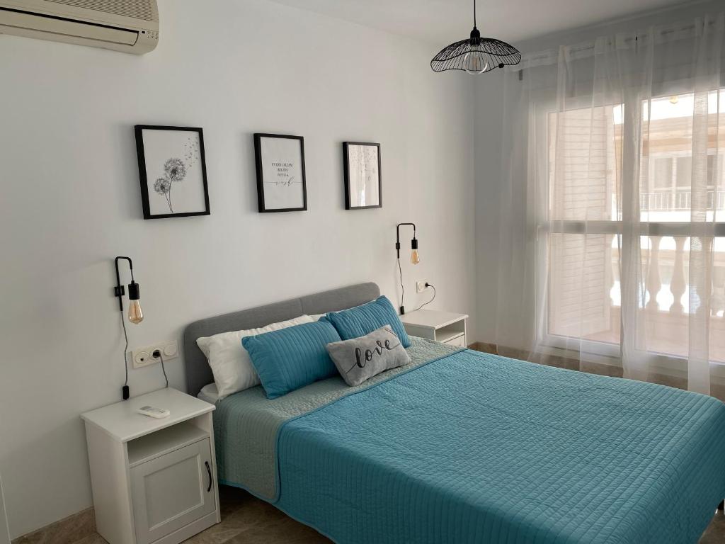 阿尔梅利马Apartamento Aguamarina的一间卧室配有一张带蓝色床单的床和一扇窗户。
