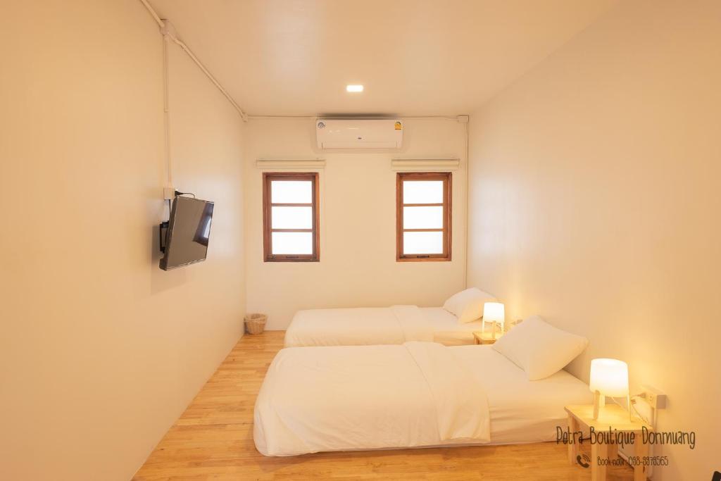 曼谷Petra Boutique Donmuang的一间带两张床的卧室和一台电视