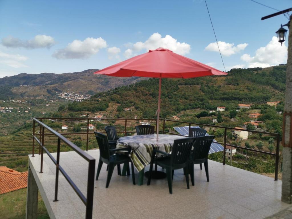 雷森迪Casa do Lagar的阳台上配有桌椅和红伞