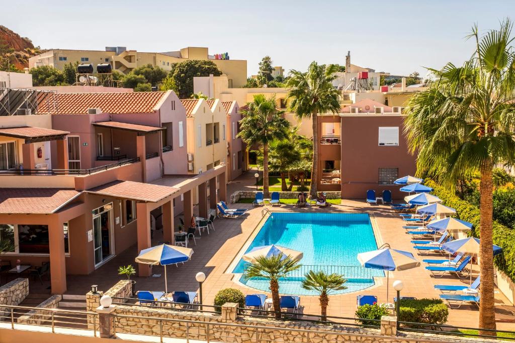 加藤-达拉特索Theos Holidays Apartments的享有带遮阳伞的度假村游泳池的空中景致