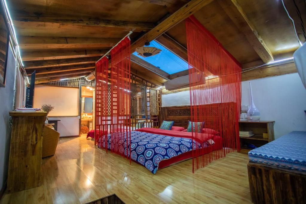 香格里拉香格里拉古城远方的家格萨吉布客栈的一间卧室设有红色的床和木制天花板。