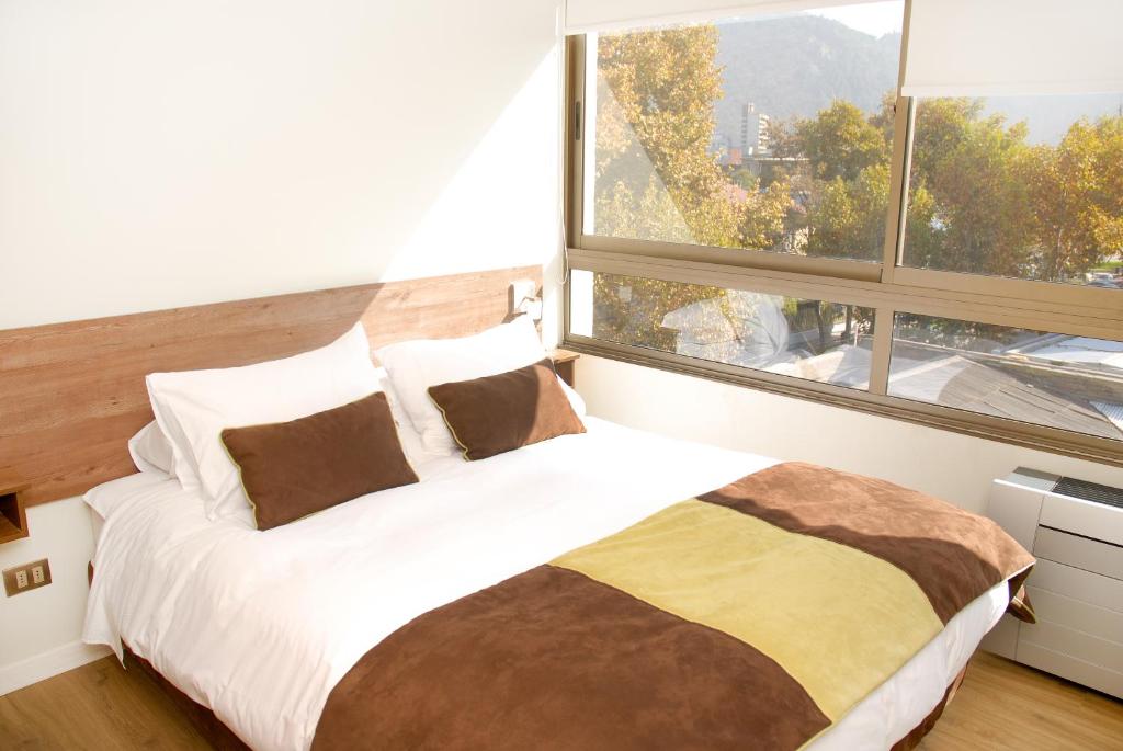 圣地亚哥普罗维登公寓酒店的一间卧室设有一张大床和大窗户