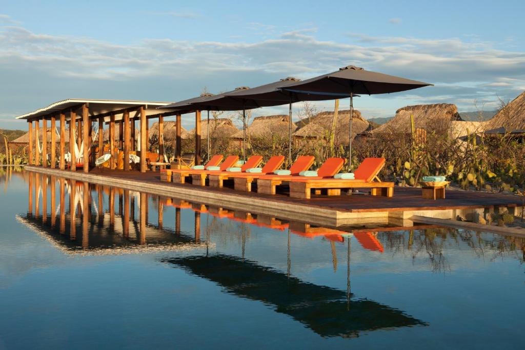 埃斯孔迪多港Hotel Escondido, Puerto Escondido, a Member of Design Hotels - Adults Only的水面上带椅子和遮阳伞的码头